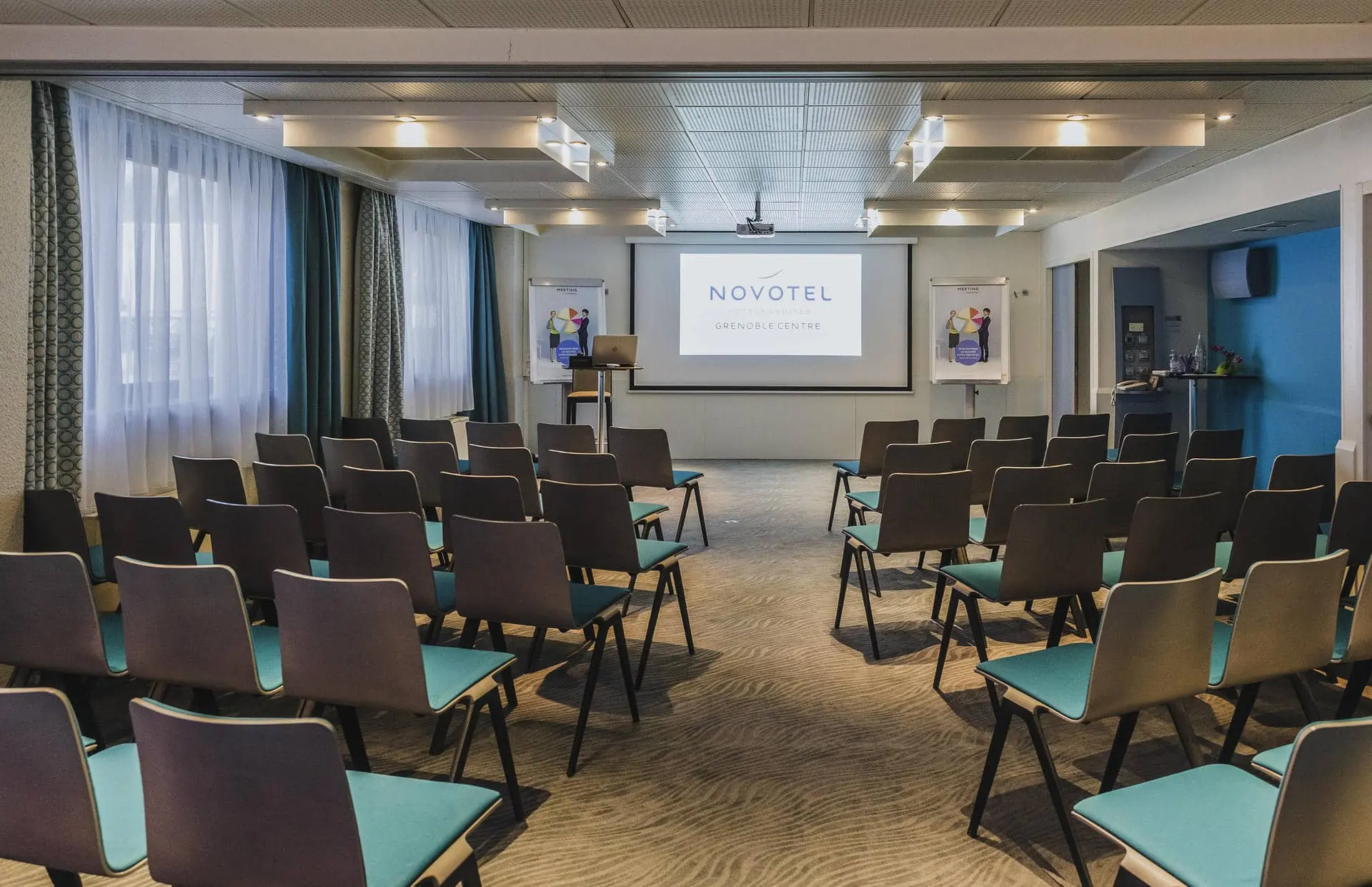 des rangées de chaises devant un écran de projection sur lequel est inscrit novotel