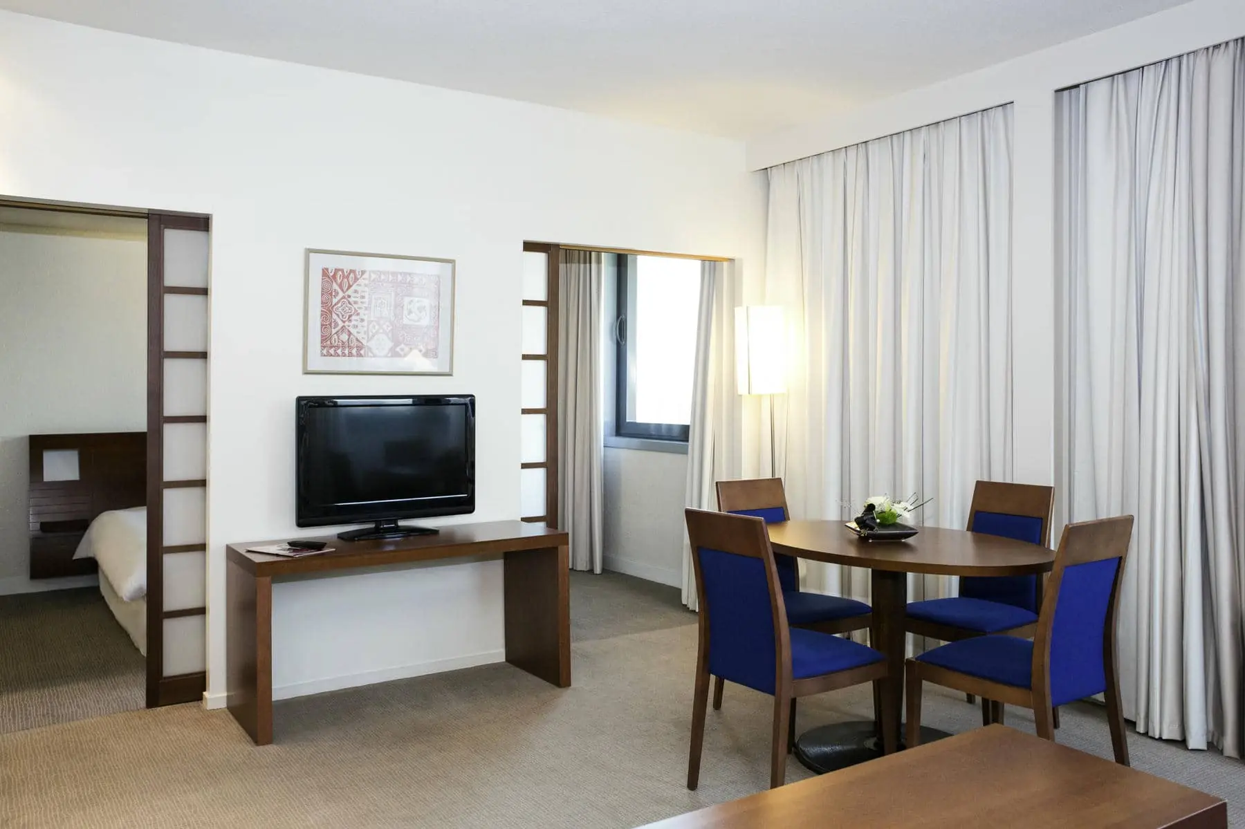 une chambre d'hôtel avec une table, des chaises et une télévision