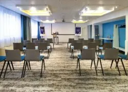 une salle de conférence avec des rangées de chaises et un écran de projection