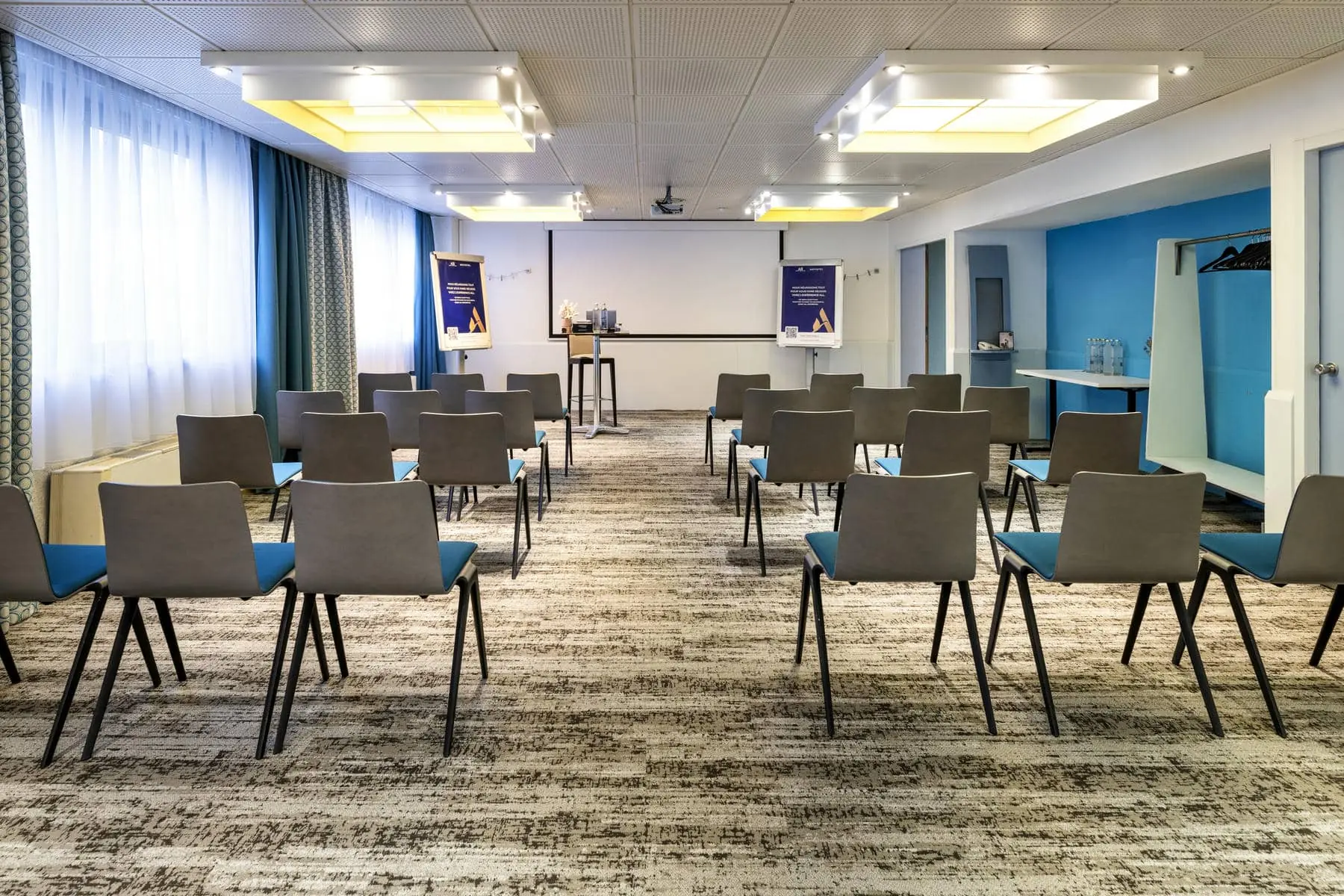 une salle de conférence avec des rangées de chaises et un écran de projection