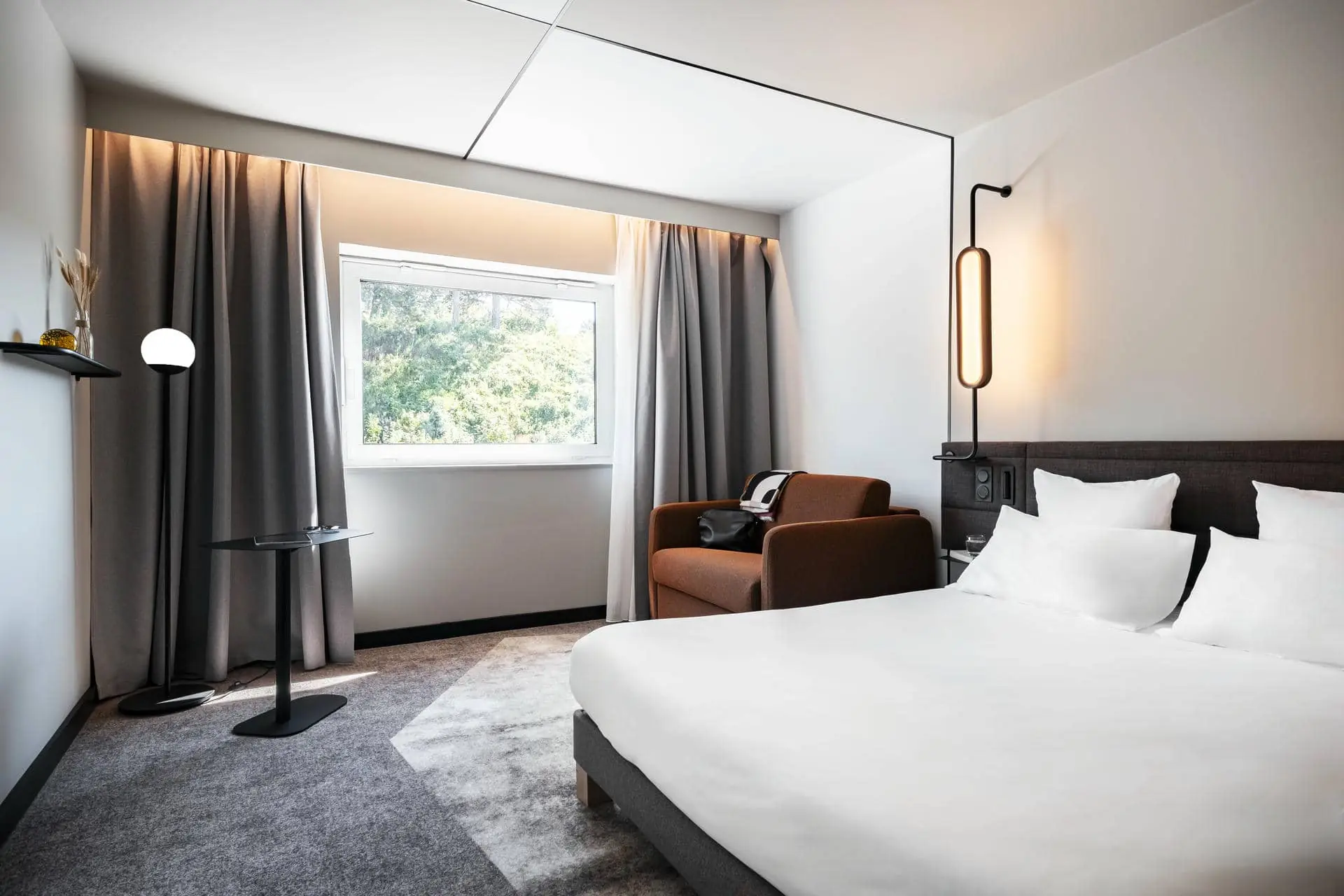 une chambre d'hôtel avec un lit, une chaise et une lampe