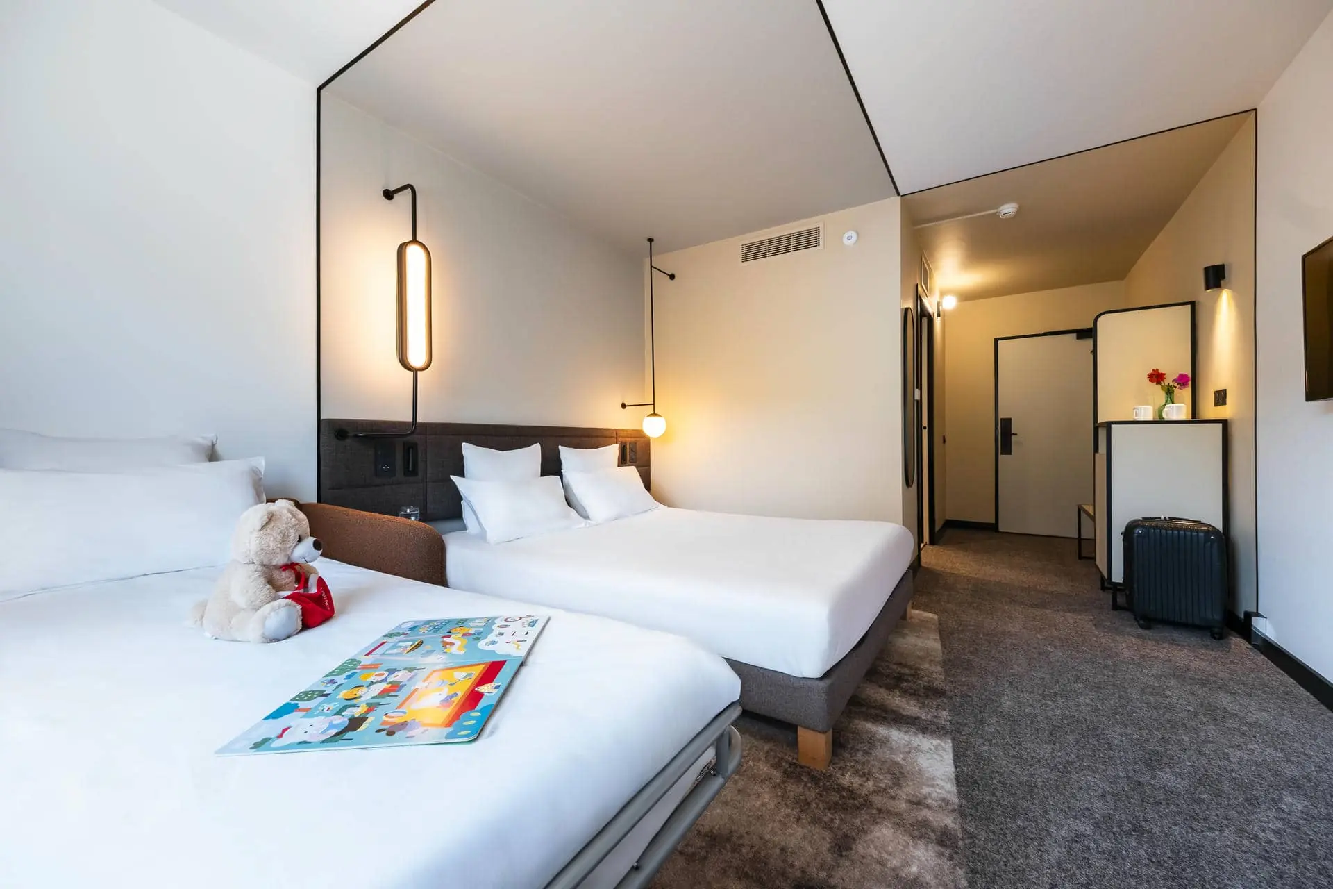 une chambre d'hôtel avec deux lits et un ours en peluche sur le lit