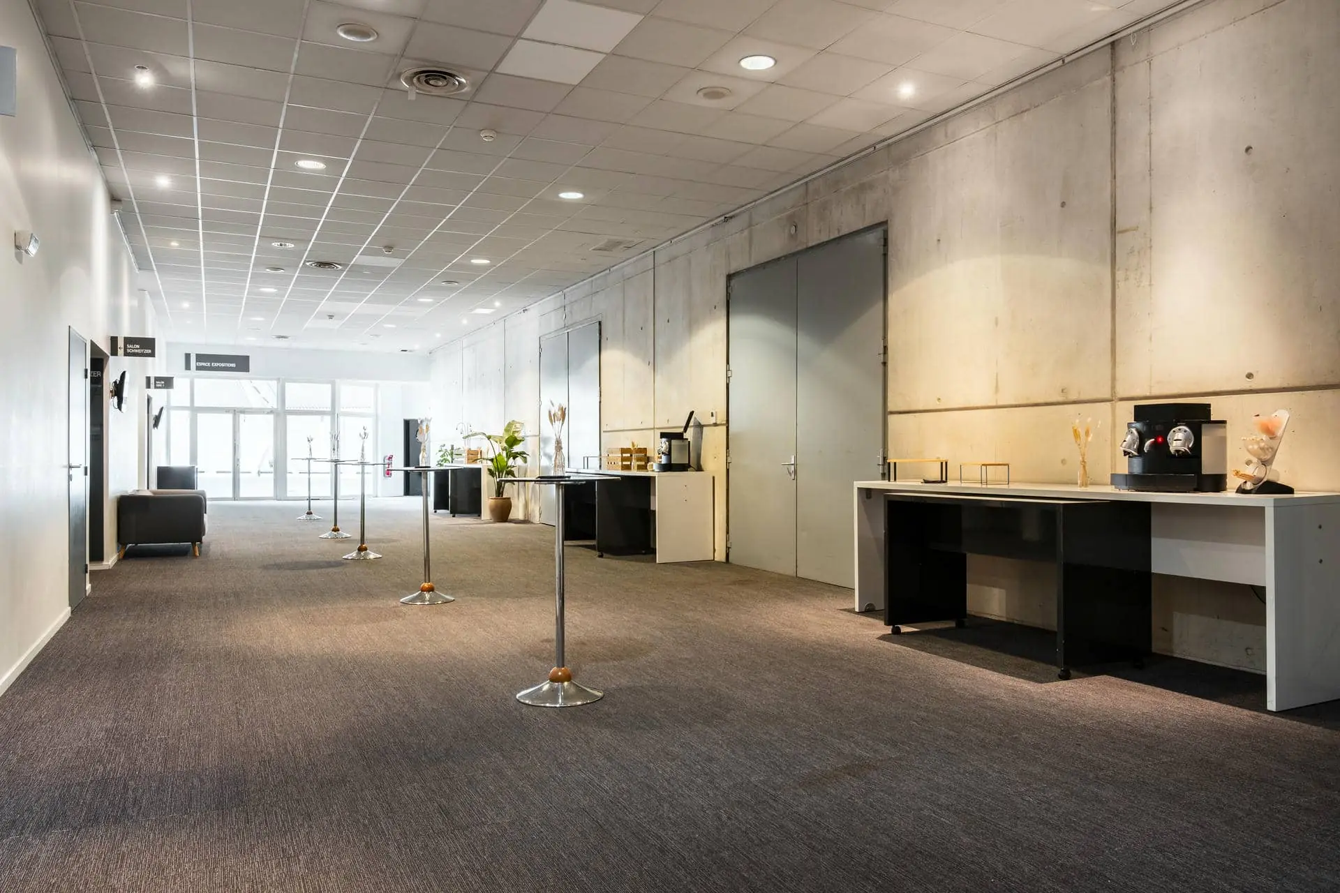a long hallway with tables and a coffee machine
