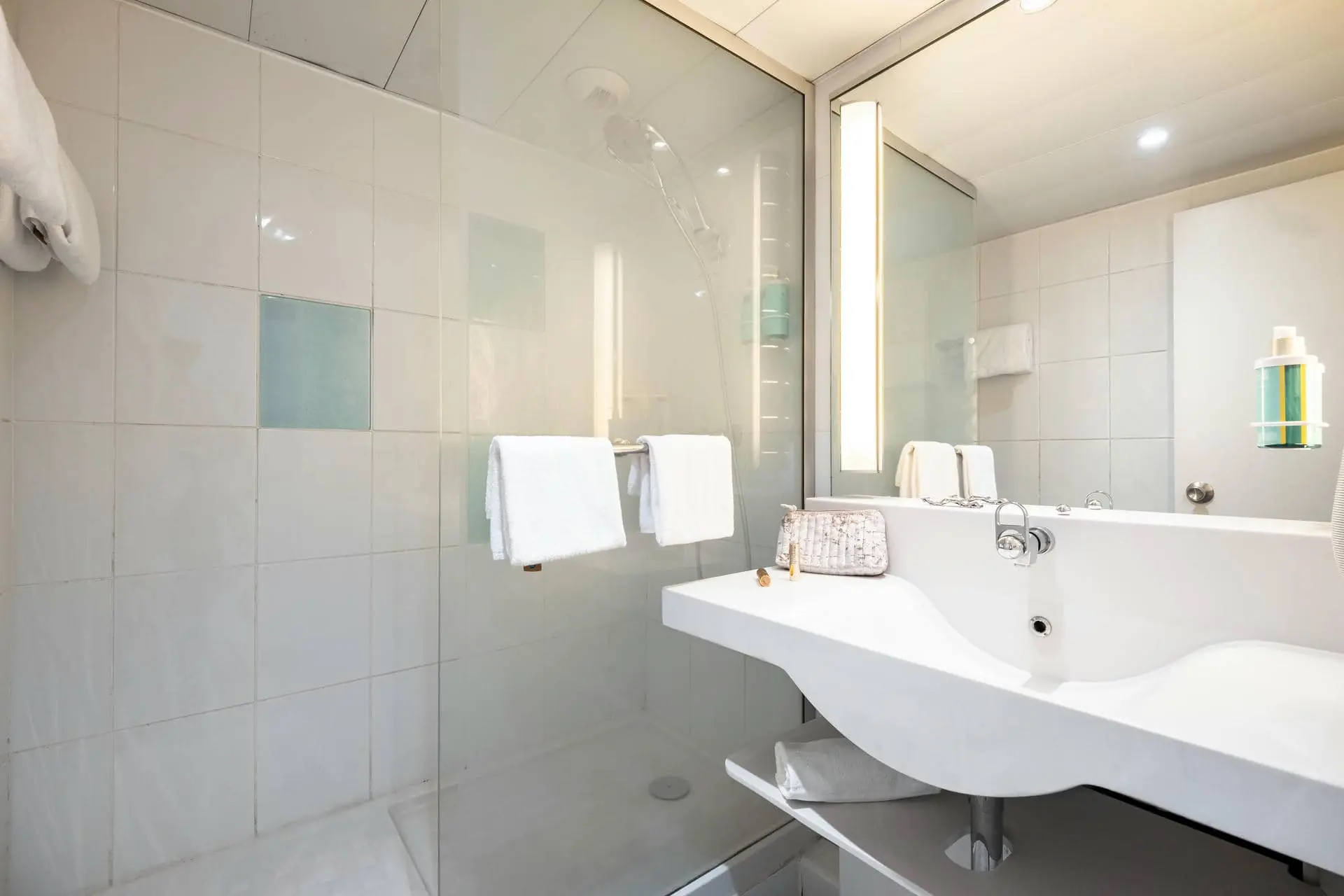 une salle de bain avec un lavabo, un miroir et une douche