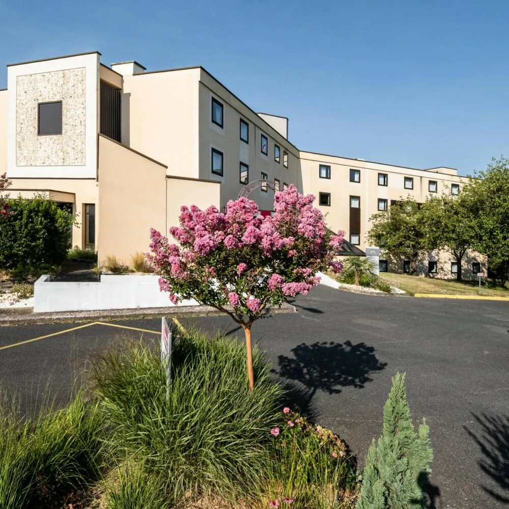 a large building with pink flowers in front of it