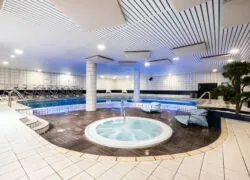 une grande piscine couverte avec un jacuzzi au milieu