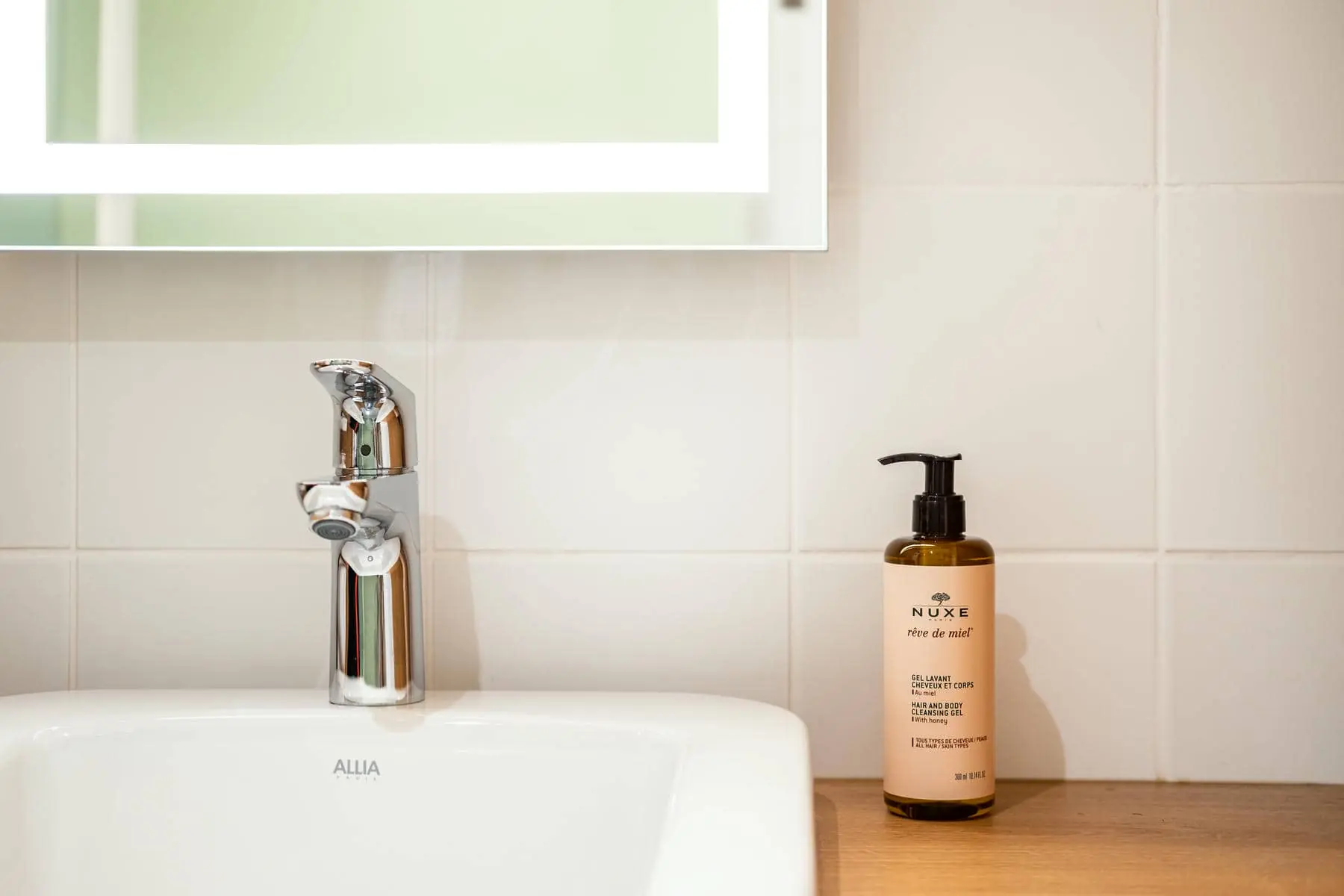 un flacon de nuxe trône sur le lavabo de la salle de bains