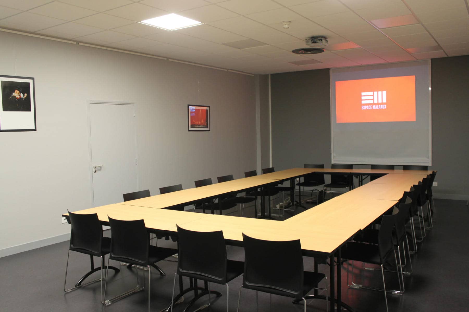une salle de conférence avec des tables et des chaises et un écran sur lequel est inscrit e11
