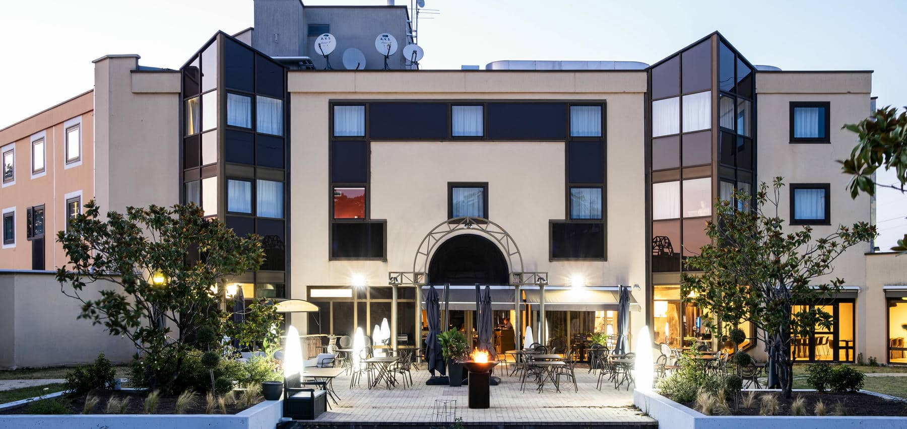 un grand bâtiment devant lequel se trouvent des tables et des chaises