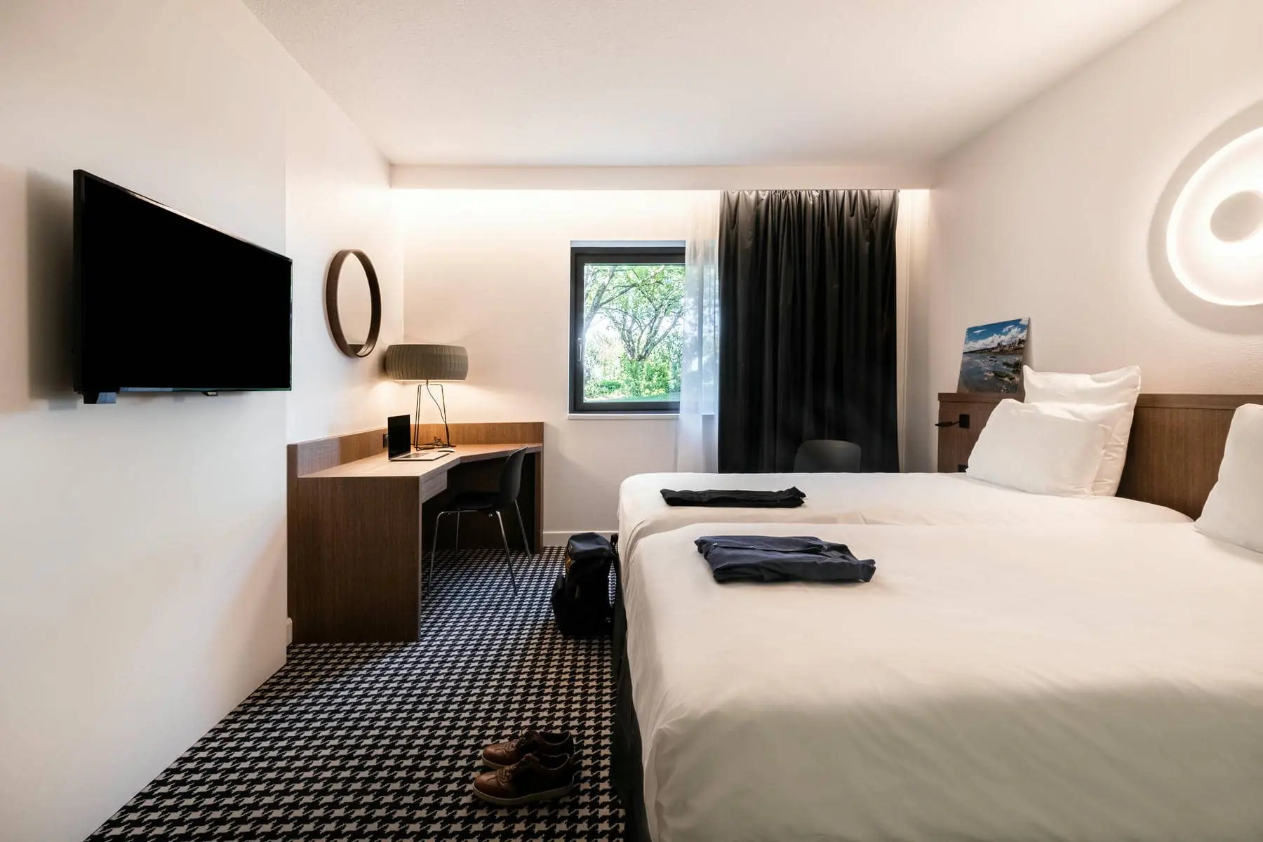 une chambre d'hôtel avec deux lits, un bureau et une télévision à écran plat