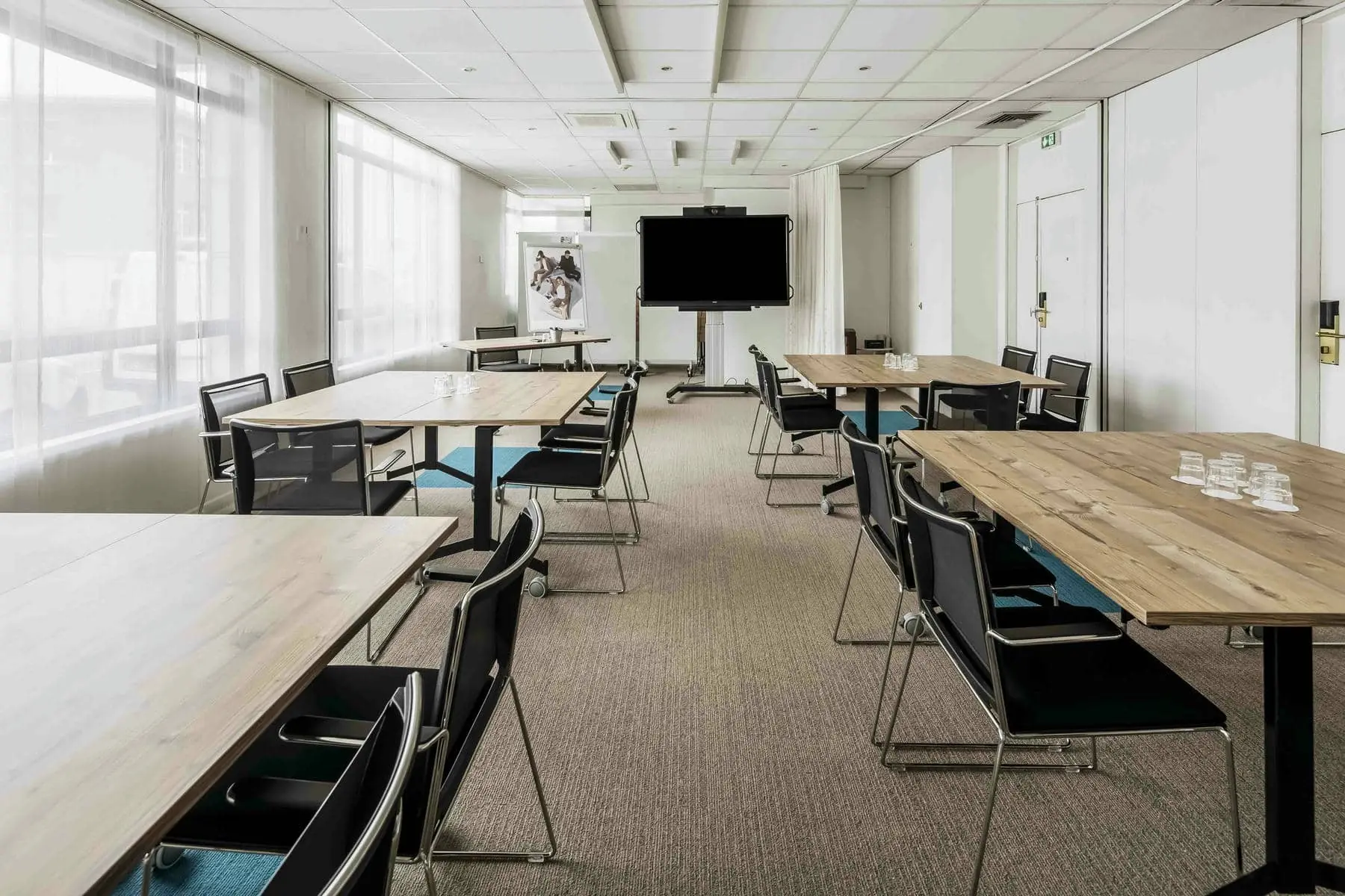 une salle de conférence avec des tables et des chaises et une télévision à écran plat