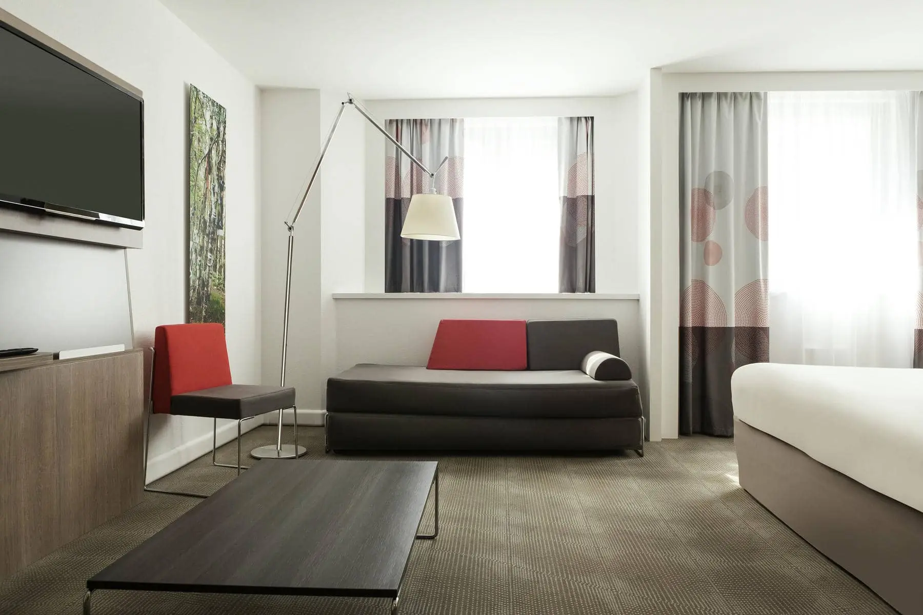 une chambre d'hôtel avec un canapé, une table et une télévision à écran plat