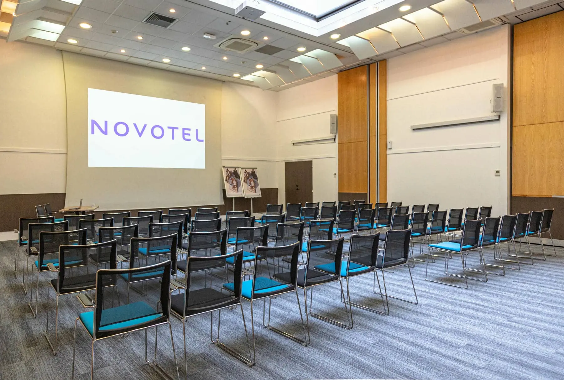 des rangées de chaises devant un écran de projection sur lequel est inscrit novotel