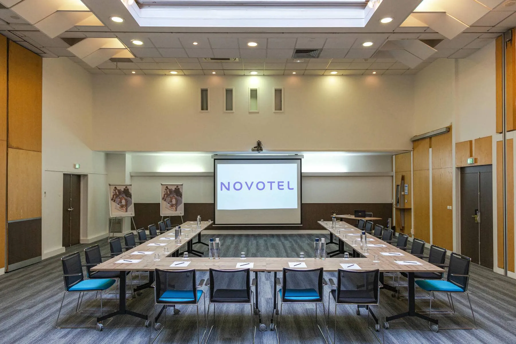 une grande salle avec un écran de projection sur lequel est inscrit novotel
