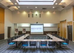 une grande salle avec un écran de projection sur lequel est inscrit novotel
