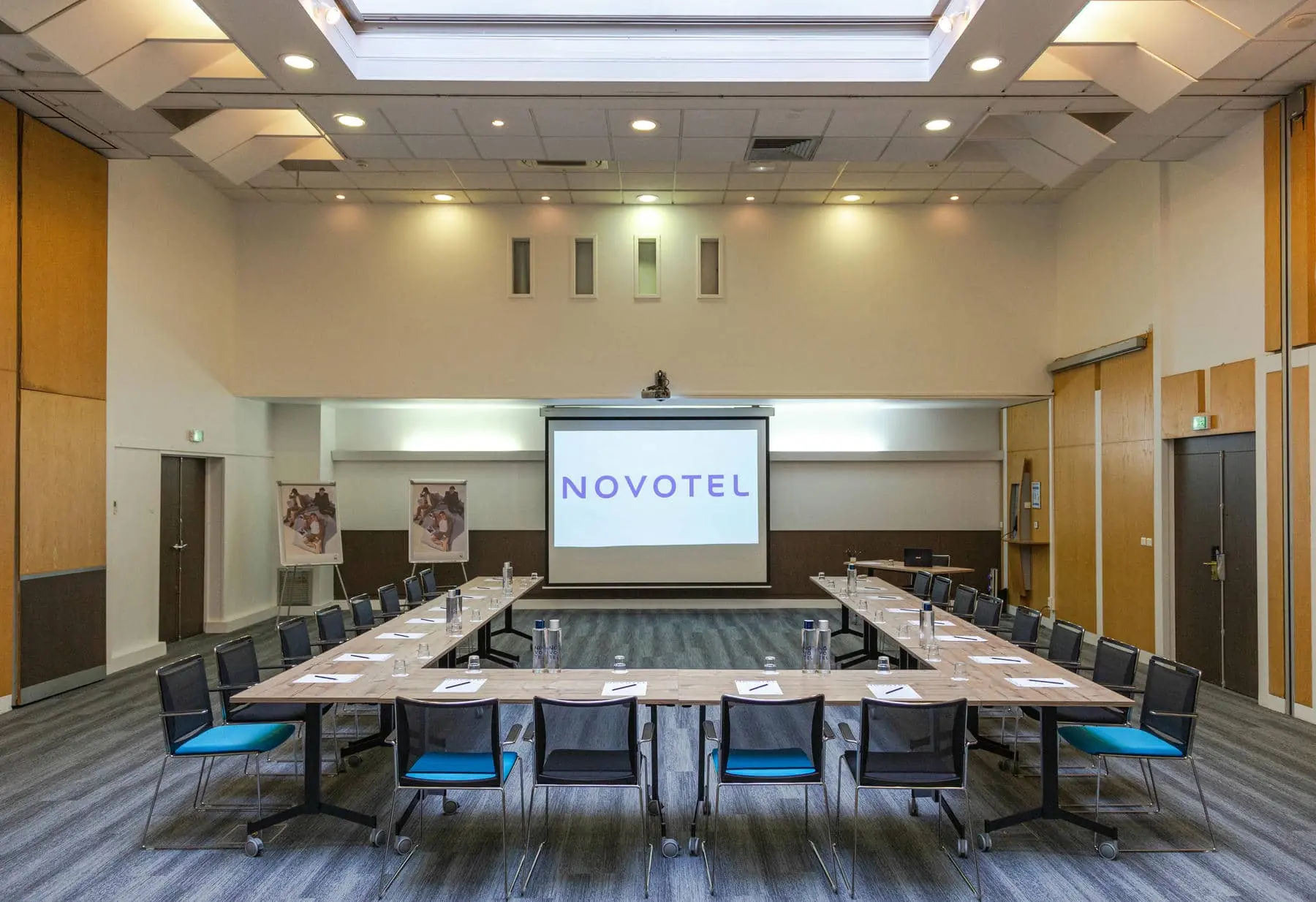 une grande salle avec un écran de projection sur lequel est inscrit novotel