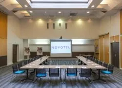 une grande salle avec un écran de projection sur lequel est inscrit novotel