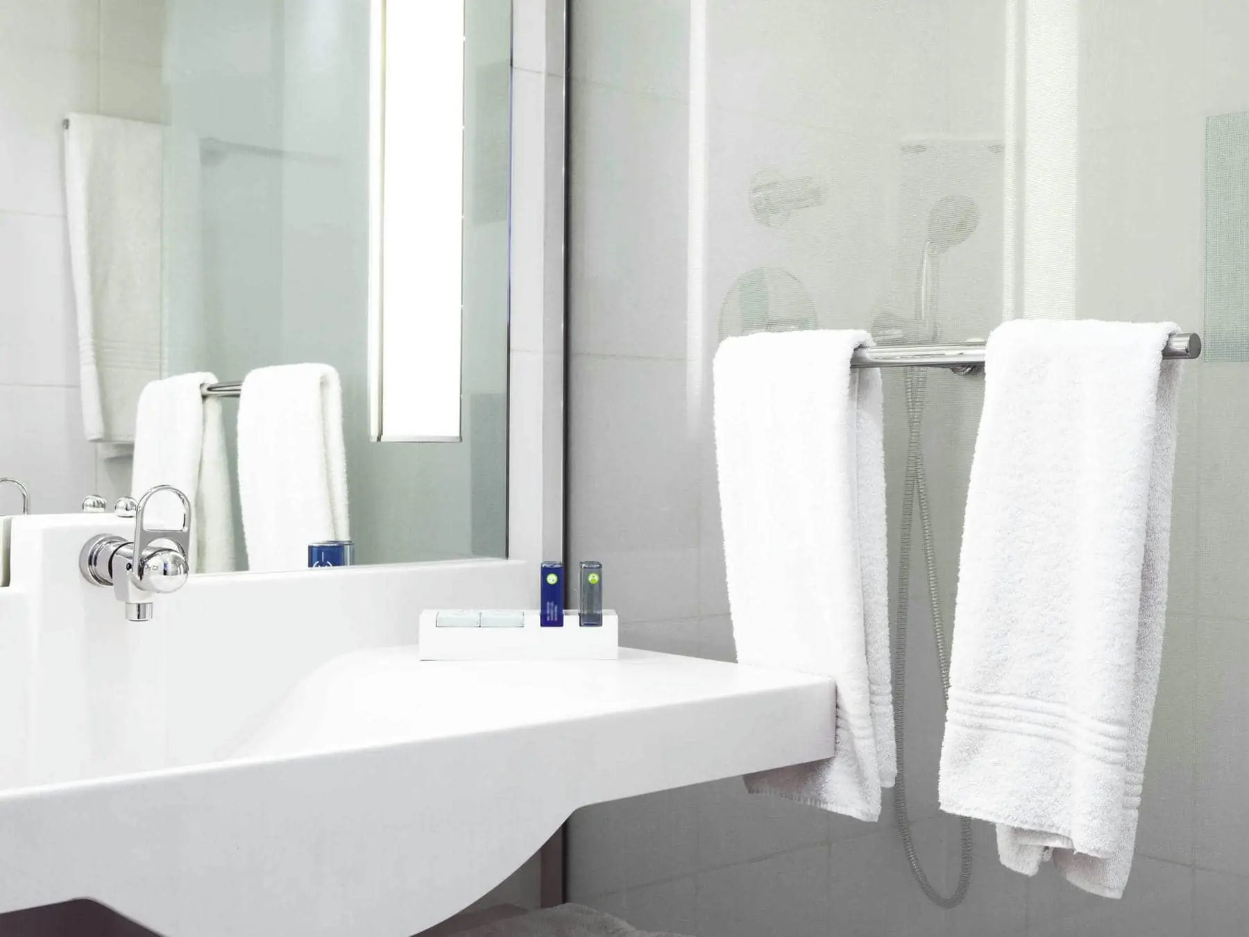 une salle de bain avec un lavabo, un miroir et un porte-serviettes