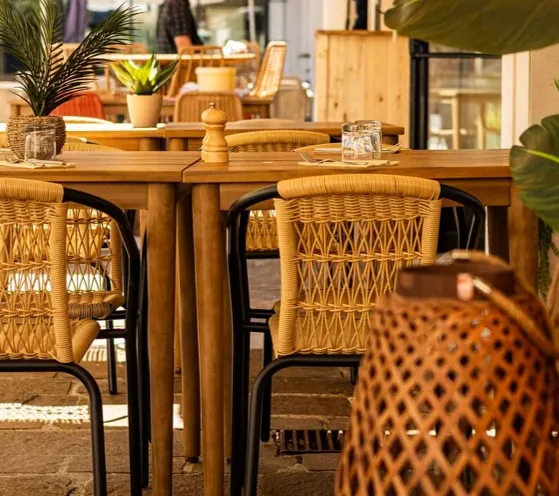 une table en bois avec des chaises en osier et une lanterne