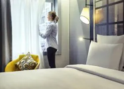 une femme dans une chambre d'hôtel regarde par la fenêtre