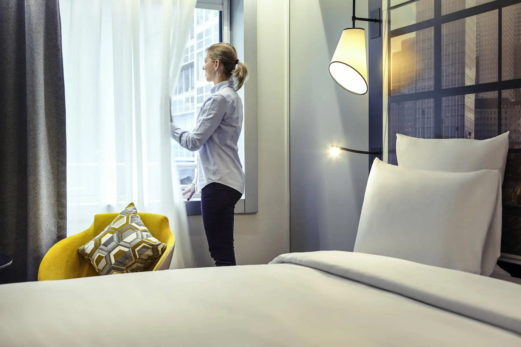 une femme dans une chambre d'hôtel regarde par la fenêtre