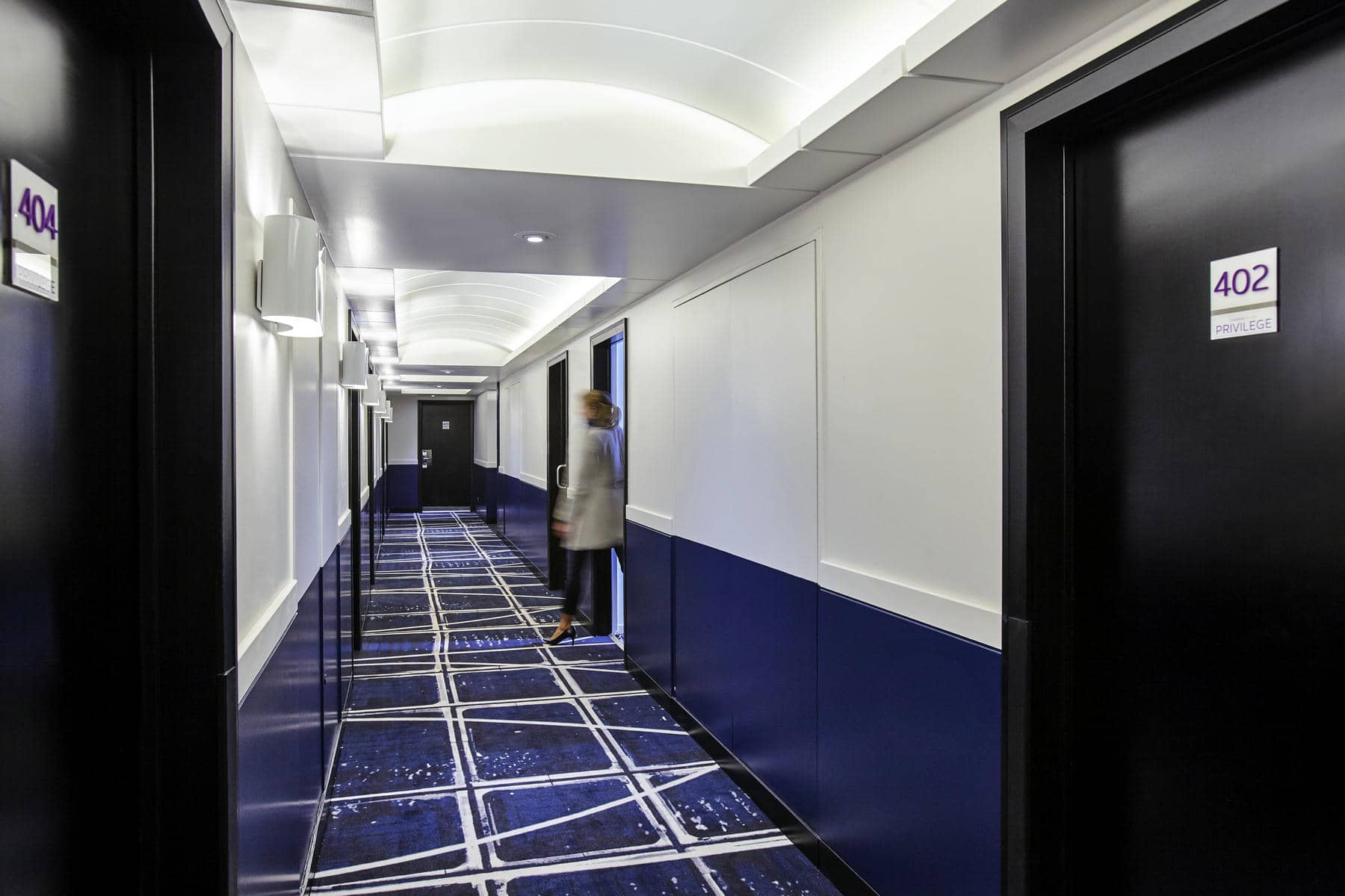 une personne marchant dans un couloir dont la porte porte porte le numéro 402