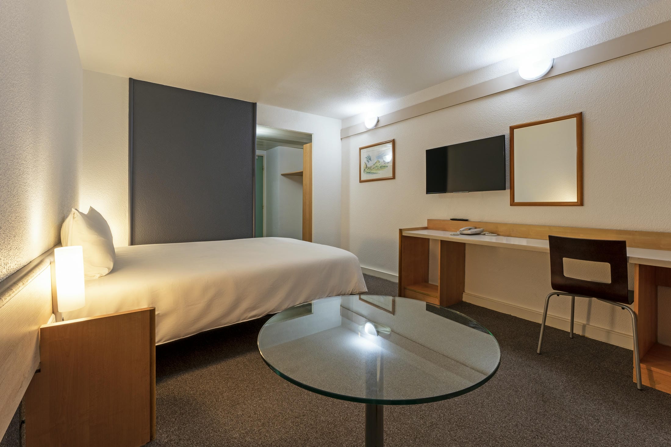 une chambre d'hôtel avec un lit simple et une table en verre