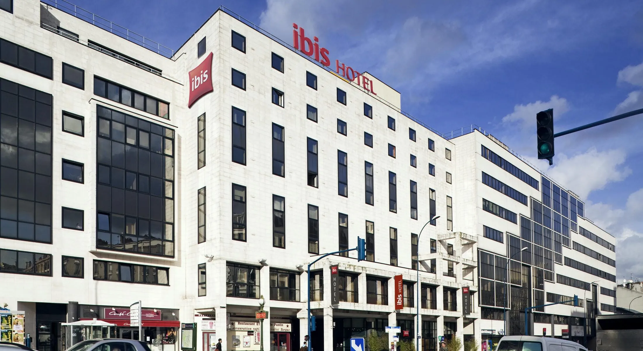 l'hôtel ibis a une enseigne rouge au sommet du bâtiment
