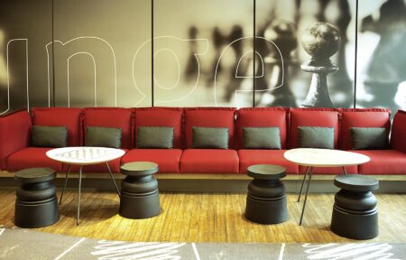 un canapé rouge avec une pièce d'échecs sur le mur derrière lui