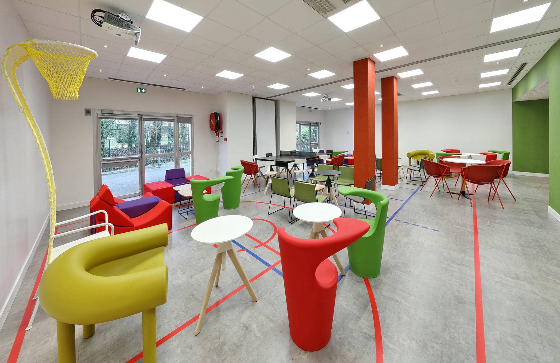 une salle avec des tables et des chaises et un projecteur au plafond