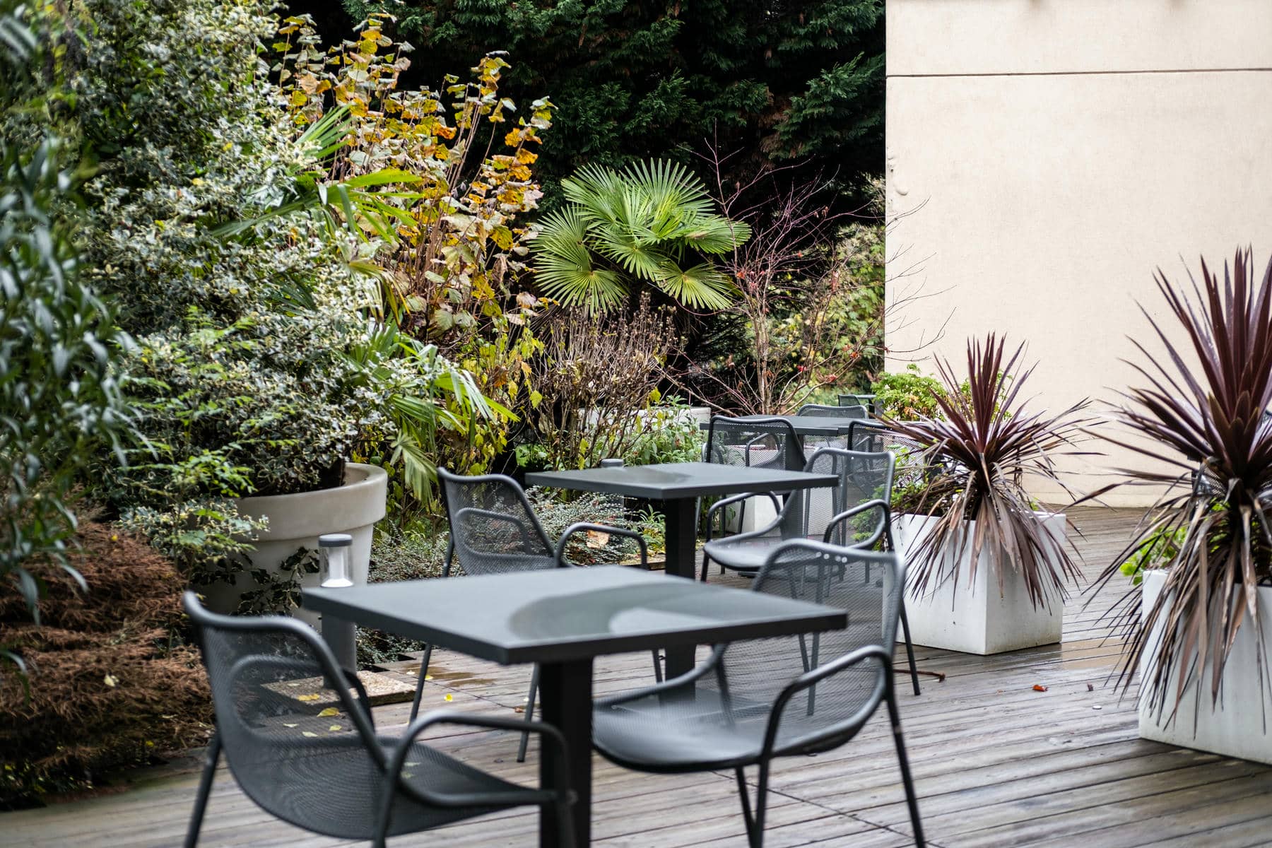 un patio avec des tables et des chaises entourées de plantes en pot