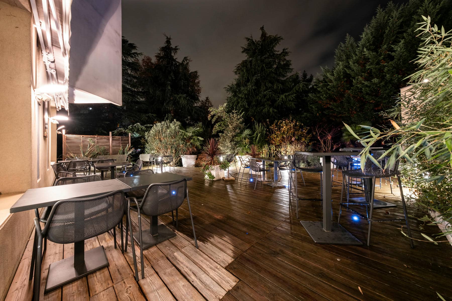 une terrasse en bois avec des tables et des chaises le soir