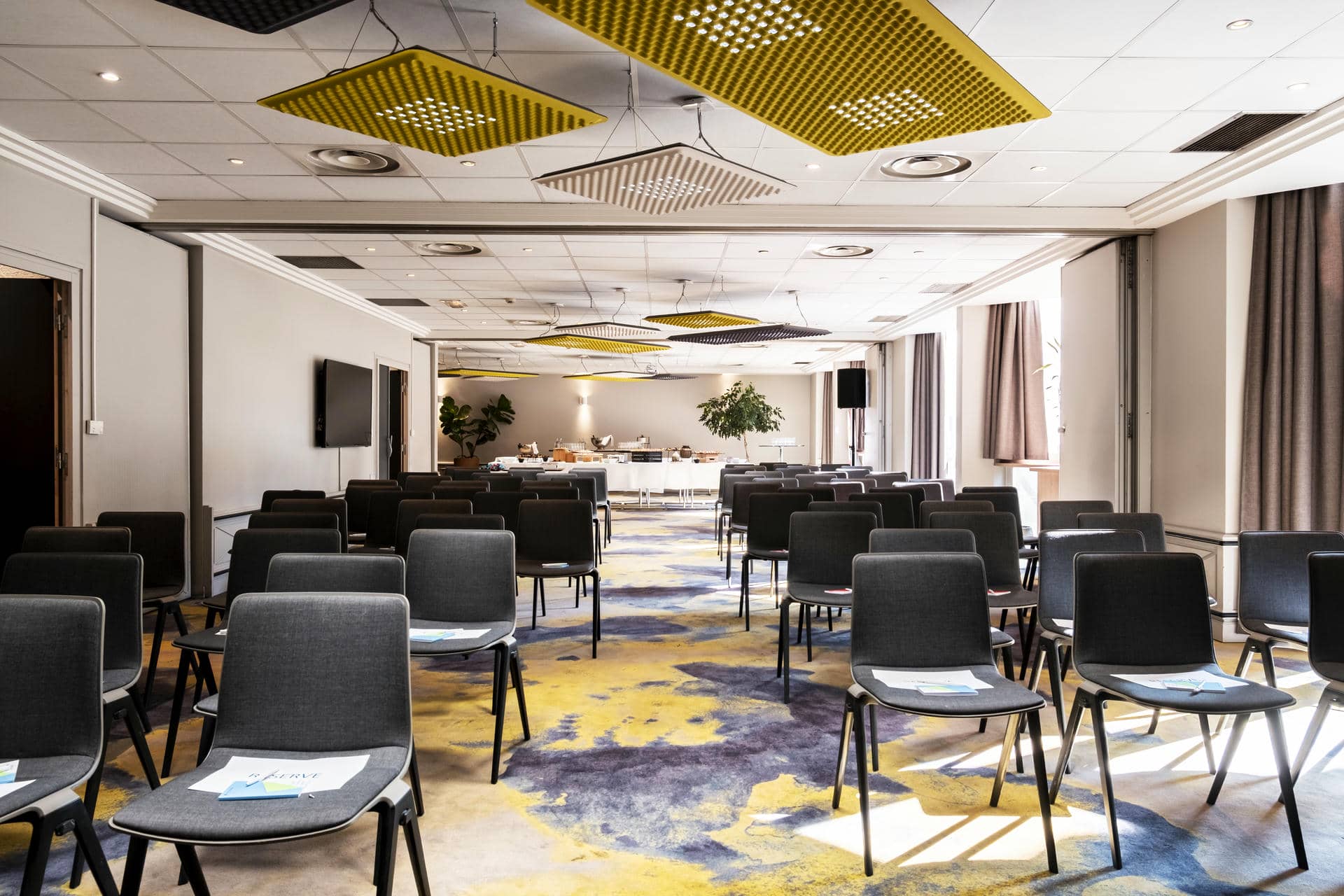 des rangées de chaises dans une salle de conférence au plafond jaune