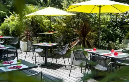 une terrasse en bois avec des tables et des chaises sous des parasols jaunes