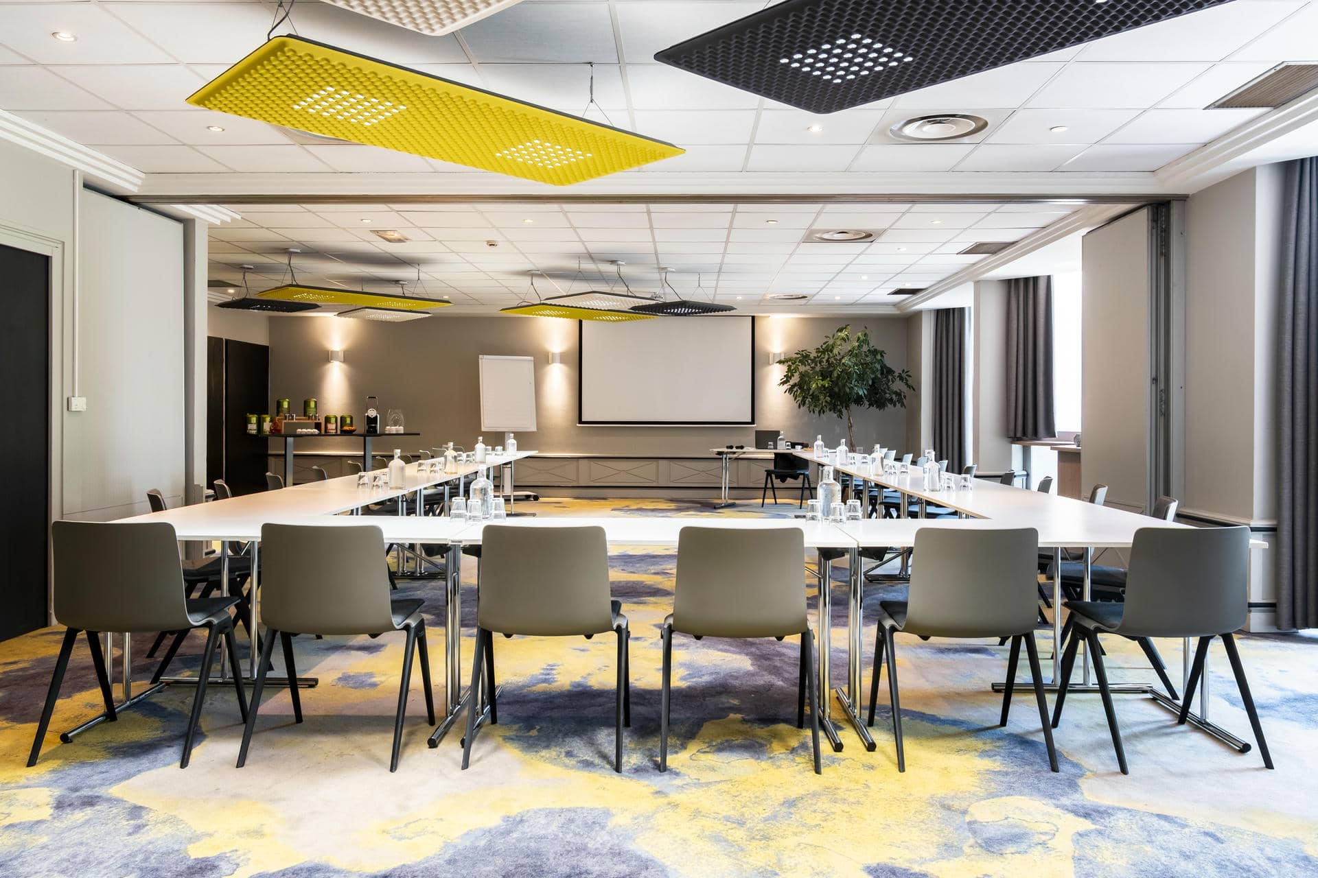 une salle de conférence avec des tables et des chaises et un écran de projection