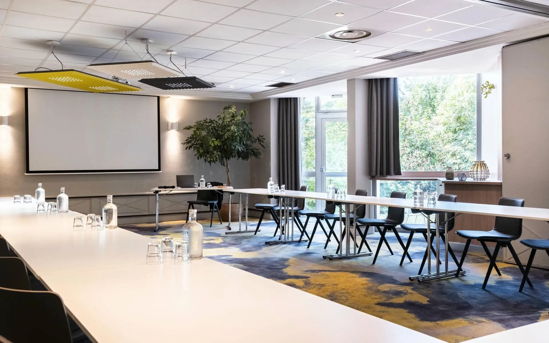 une salle de conférence avec des tables et des chaises et un écran de projection