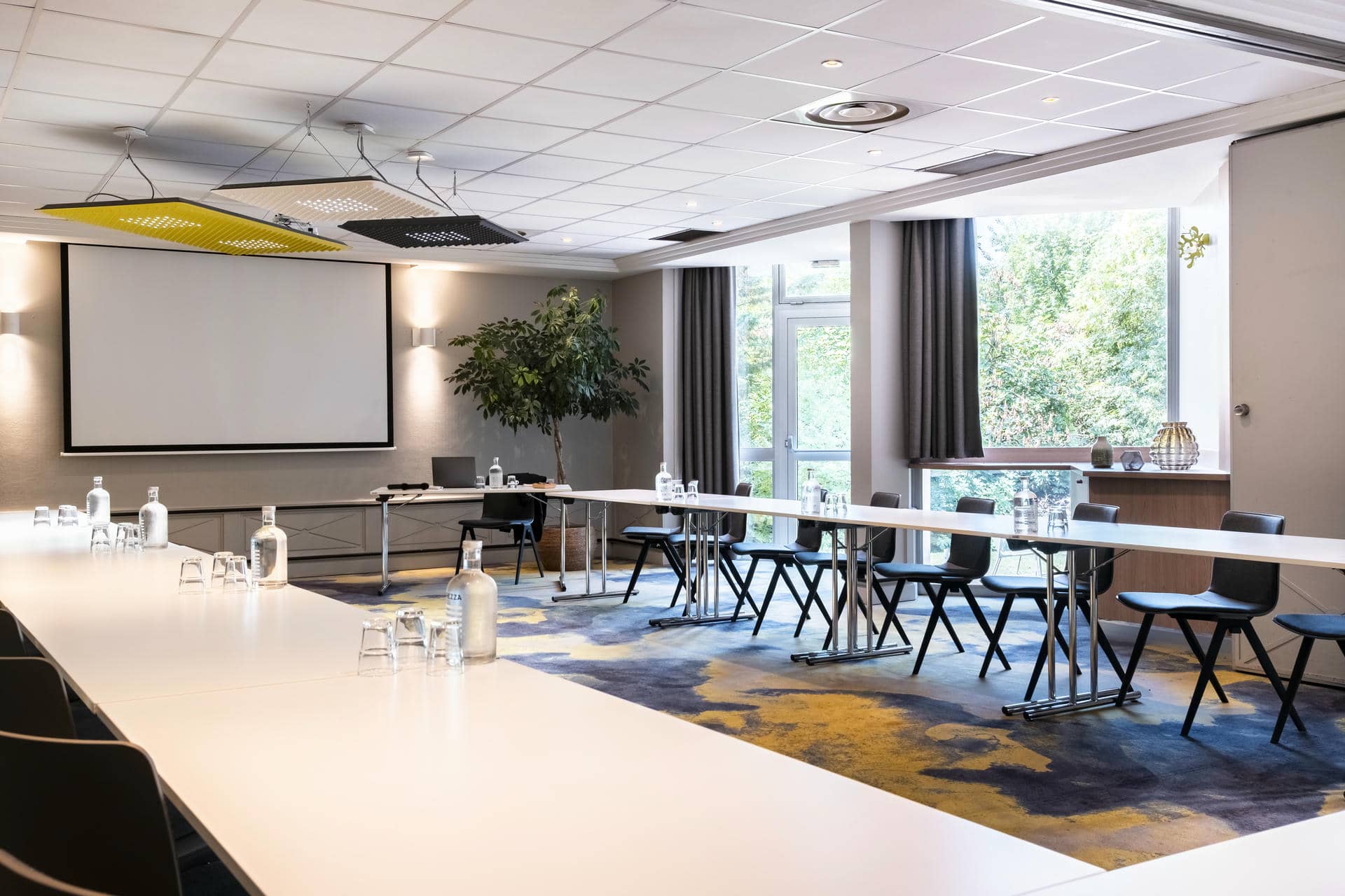 une salle de conférence avec des tables et des chaises et un écran de projection