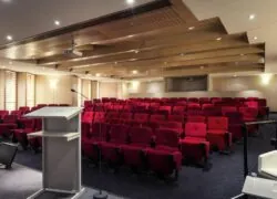 un grand auditorium avec des sièges rouges et un podium