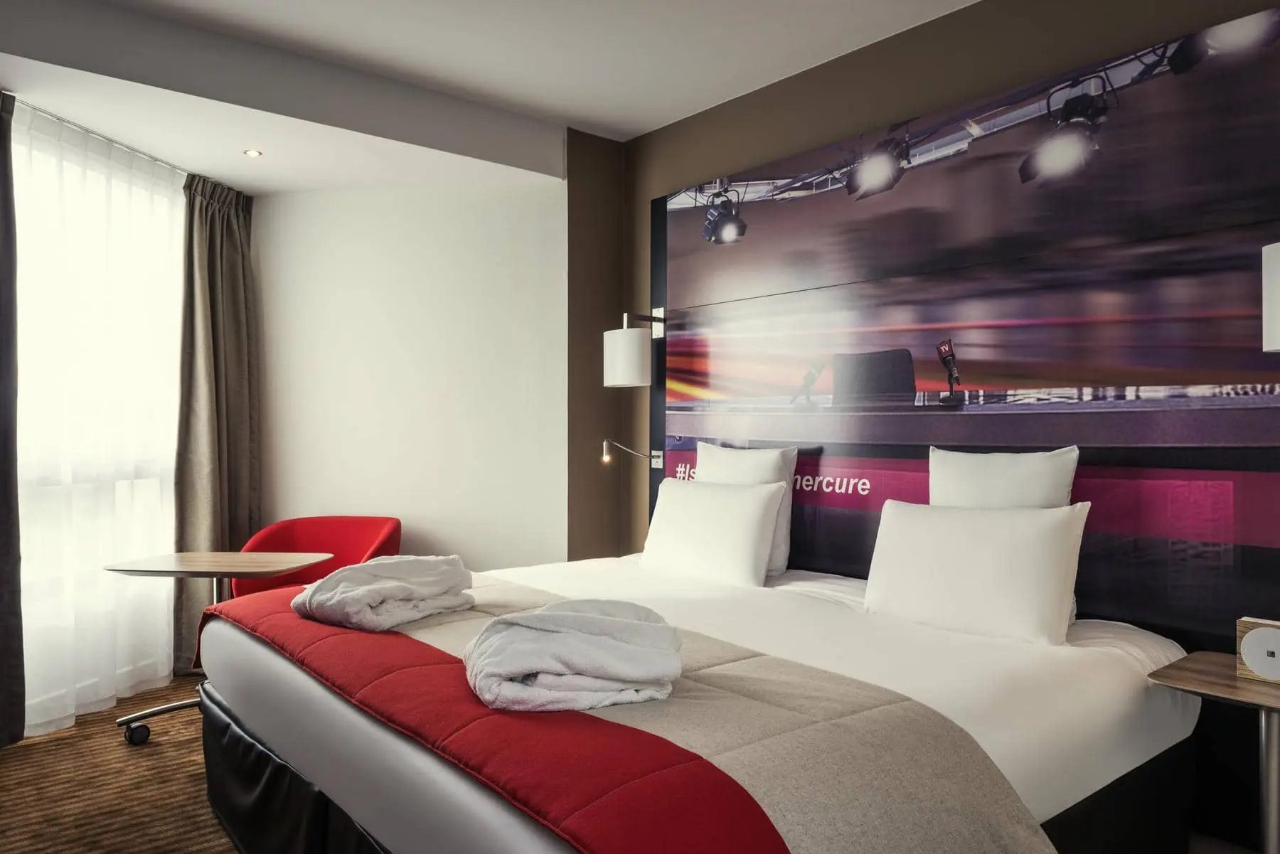 une chambre d'hôtel mercure avec deux lits et une chaise rouge