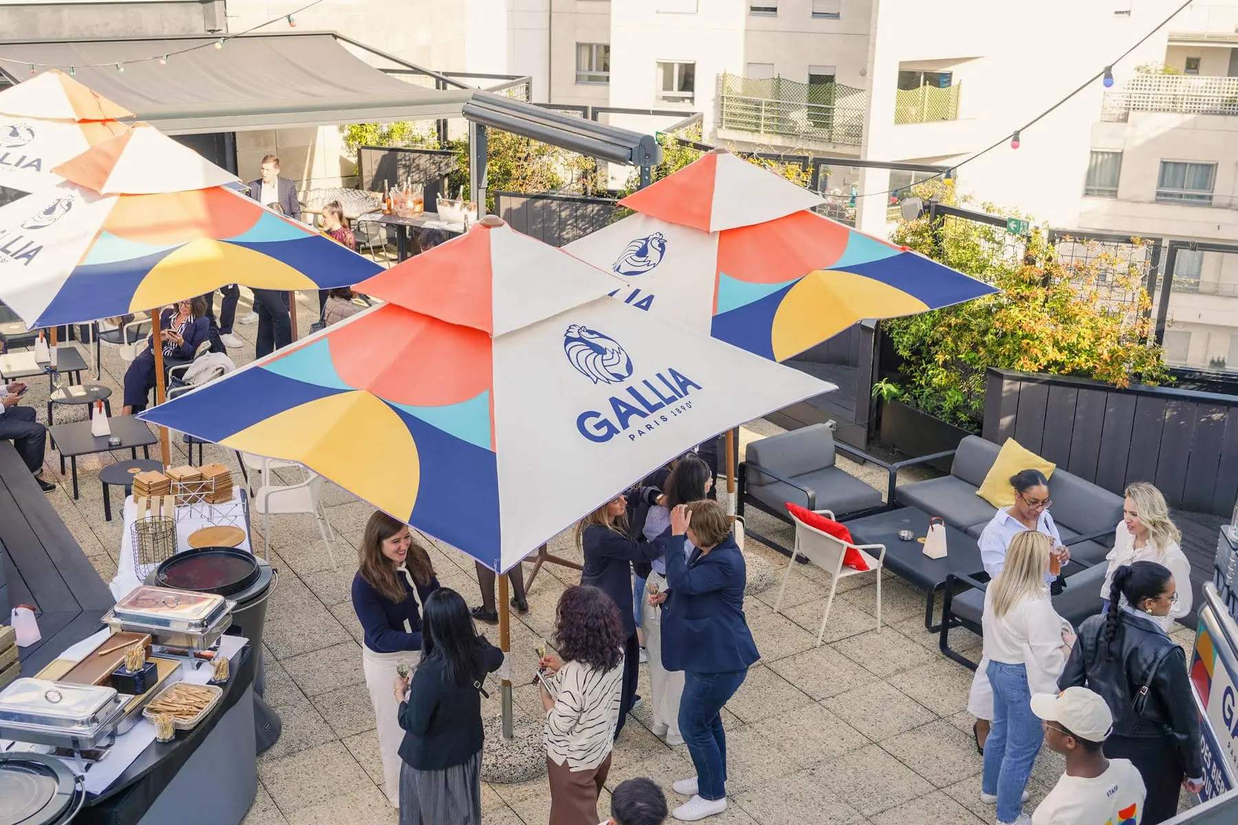 un groupe de personnes est rassemblé sous un parapluie portant l'inscription gallia