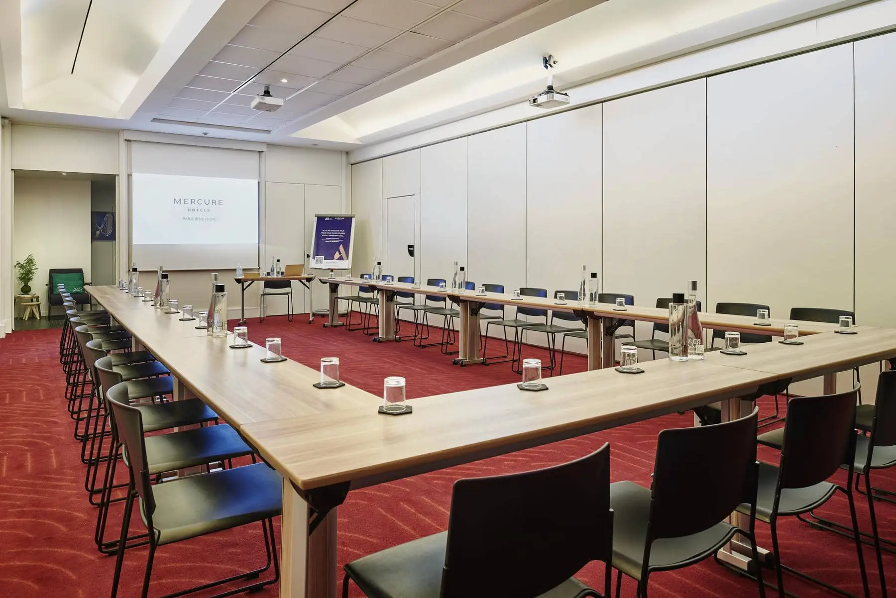 une salle de conférence de l'hôtel mercure avec tables et chaises