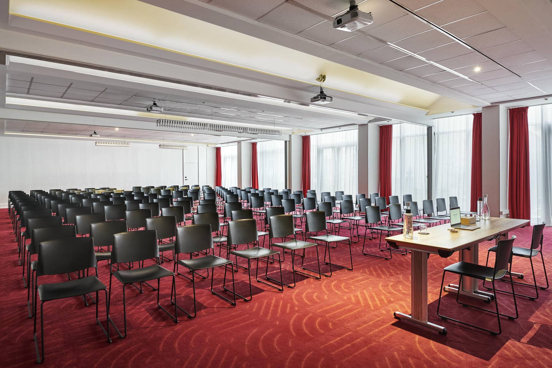 une salle de conférence avec des rangées de chaises et une table