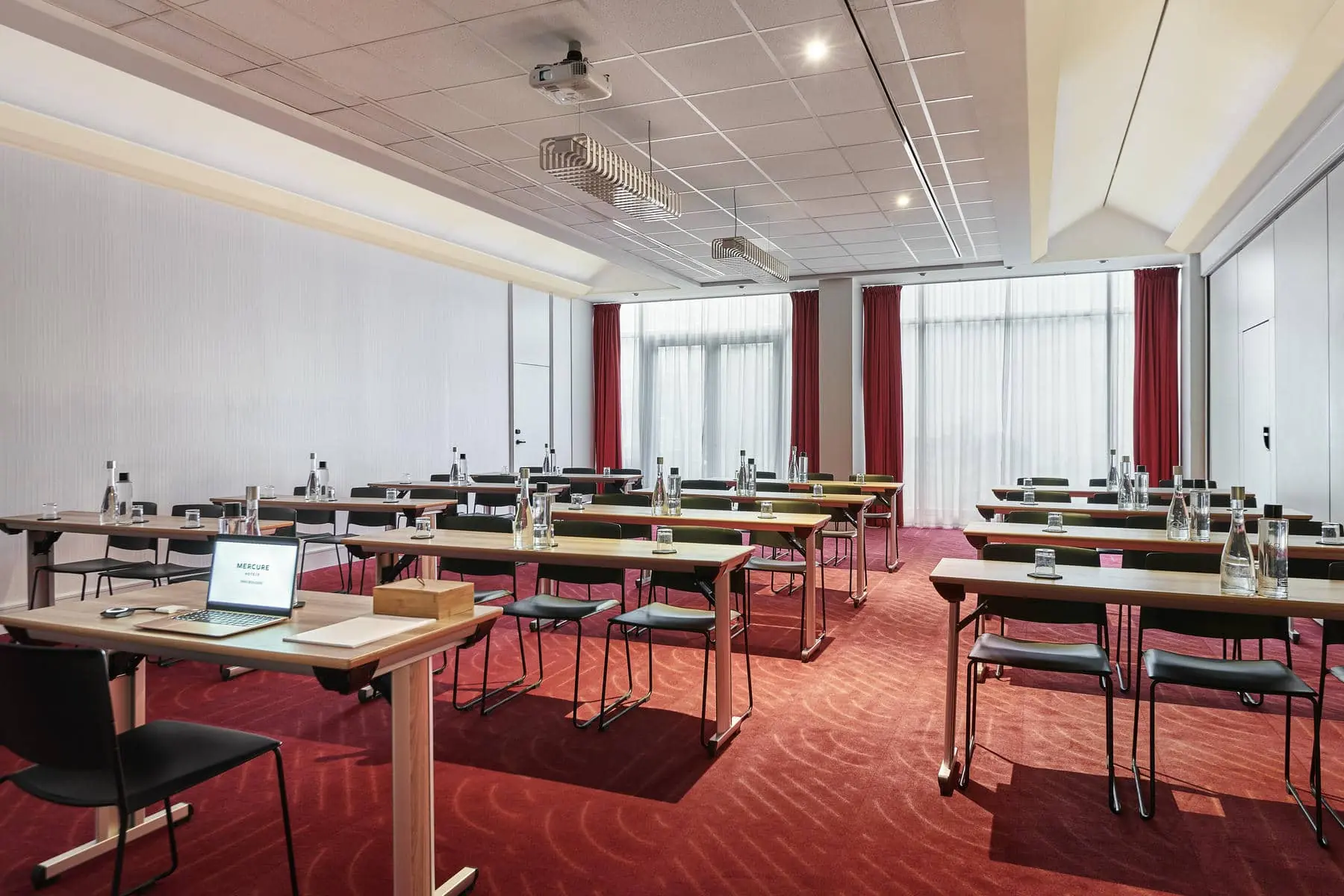 une salle de conférence avec des rangées de tables et de chaises et un ordinateur portable sur la table