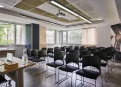 une salle de conférence avec des chaises noires et un projecteur