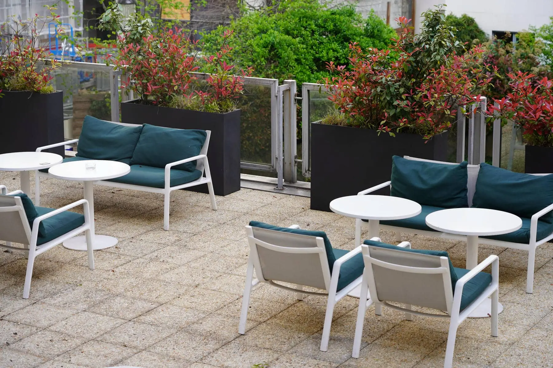 un patio avec des chaises et des tables avec des coussins verts
