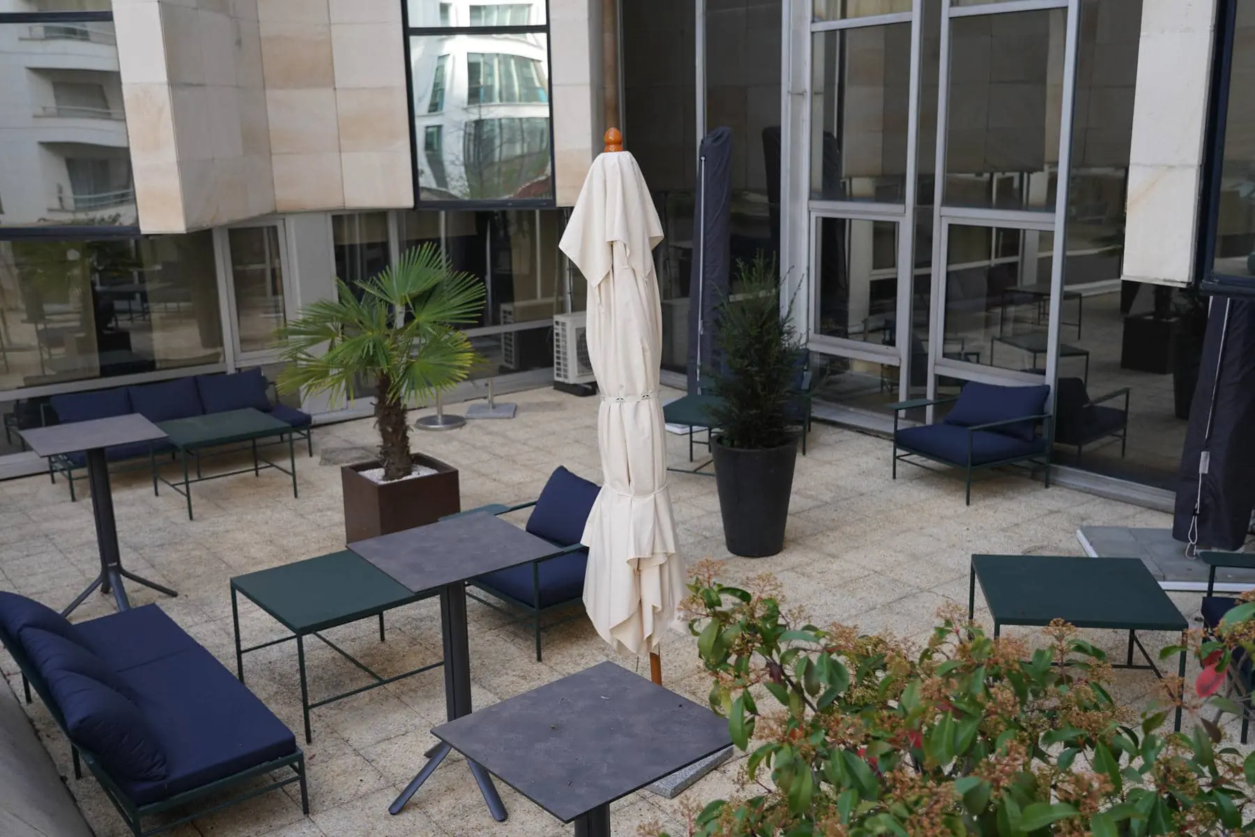 un patio avec des tables et des chaises et un parasol blanc