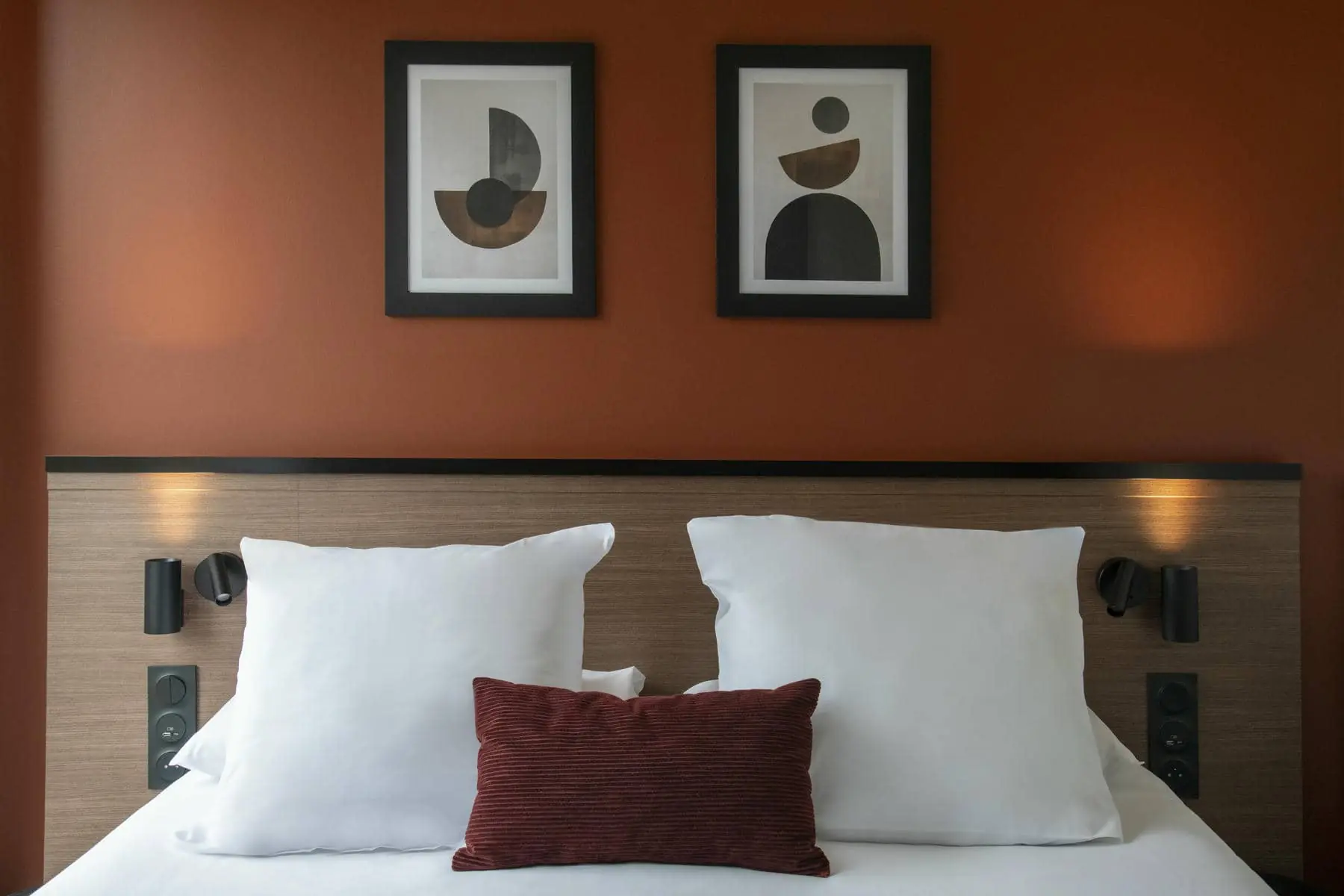 un lit avec deux tableaux sur le mur qui le surplombe