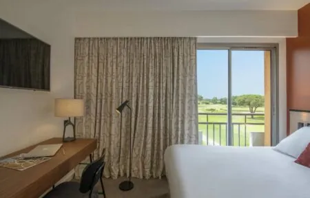 une chambre d'hôtel avec un lit, un bureau et une télévision à écran plat