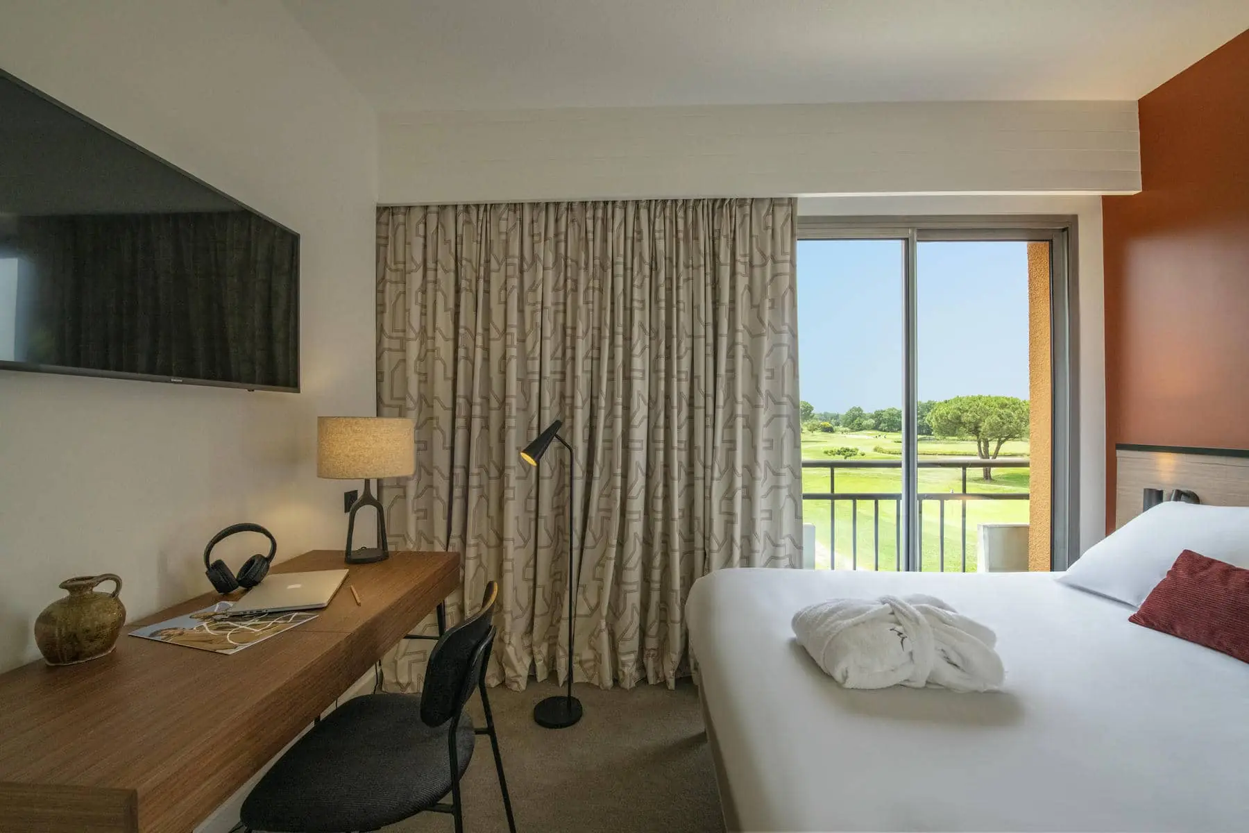 une chambre d'hôtel avec un lit, un bureau et une télévision à écran plat