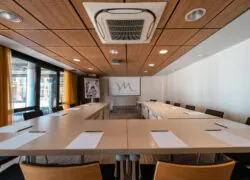 une salle de conférence avec un écran de projection sur lequel figure la lettre m